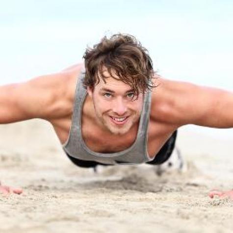 Fit und gesund mann macht liegestütze im sand Fit und gesund mann macht liegestütze im sand
