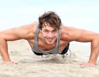 Fit und gesund mann macht liegestütze im sand