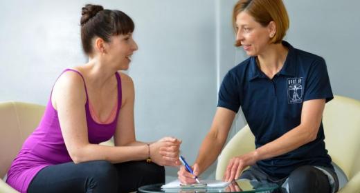 Fitnesscheck Trainerin unterhält sich mit Mitglied über die Auswertung